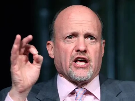 Jim Cramer wearing grey suit and pink shirt,he is giving a speech