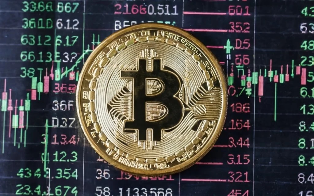 Bitcoin behind computer screen, showing candles of crypto market