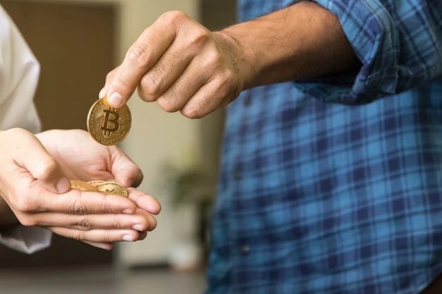 Image of a person giving physical bitcoin to someone else