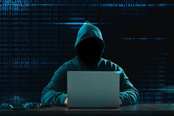 Hacker sitting with his laptop, dark themed background