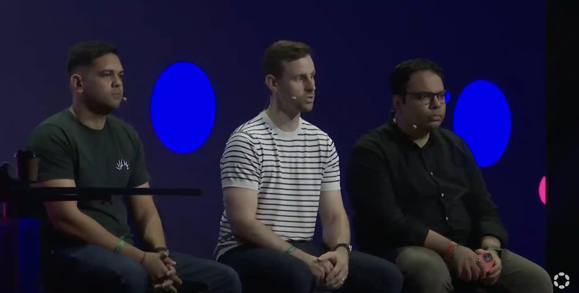 Image of 3 men, Cameron, Gautam and Alistair, sitting on stage at Polkadot event